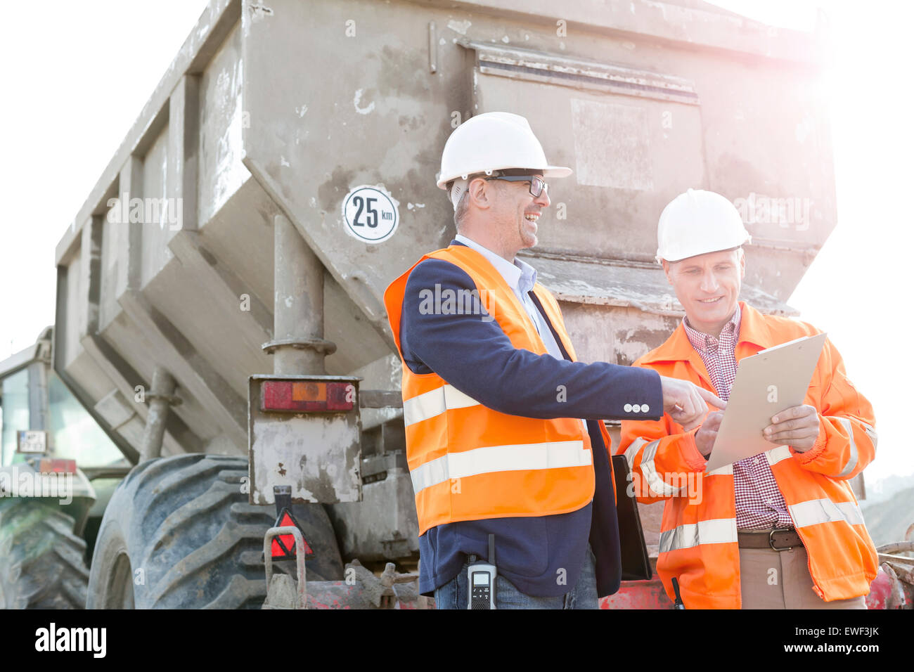 Happy architects discussing over clipboard by construction truck Stock Photo