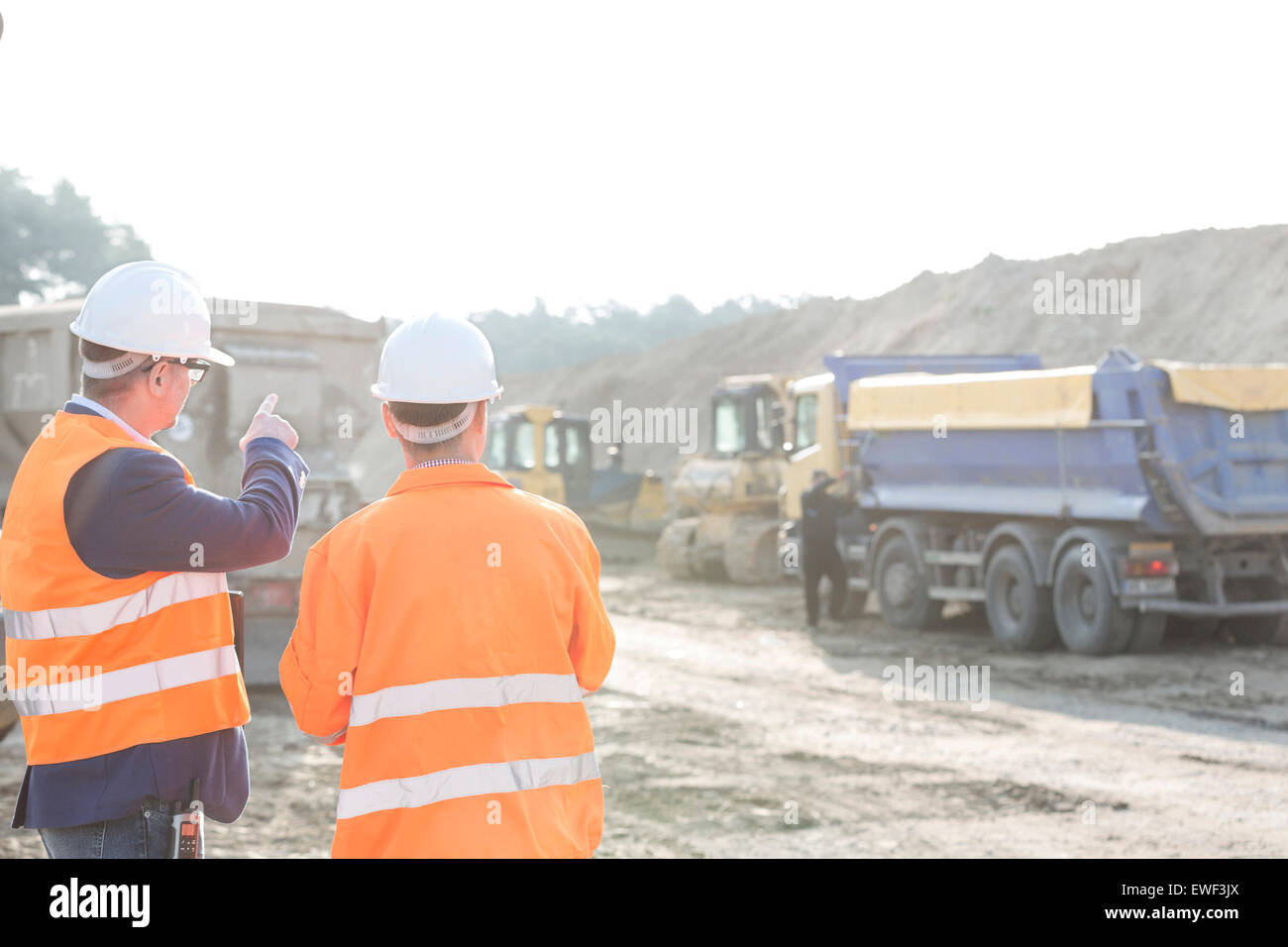 Supervisor explaining plan to colleague at construction site Stock Photo