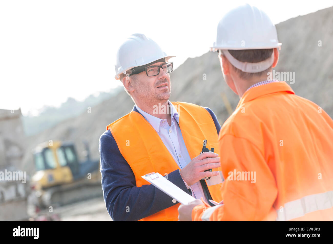 Architects discussing at construction site on sunny day Stock Photo