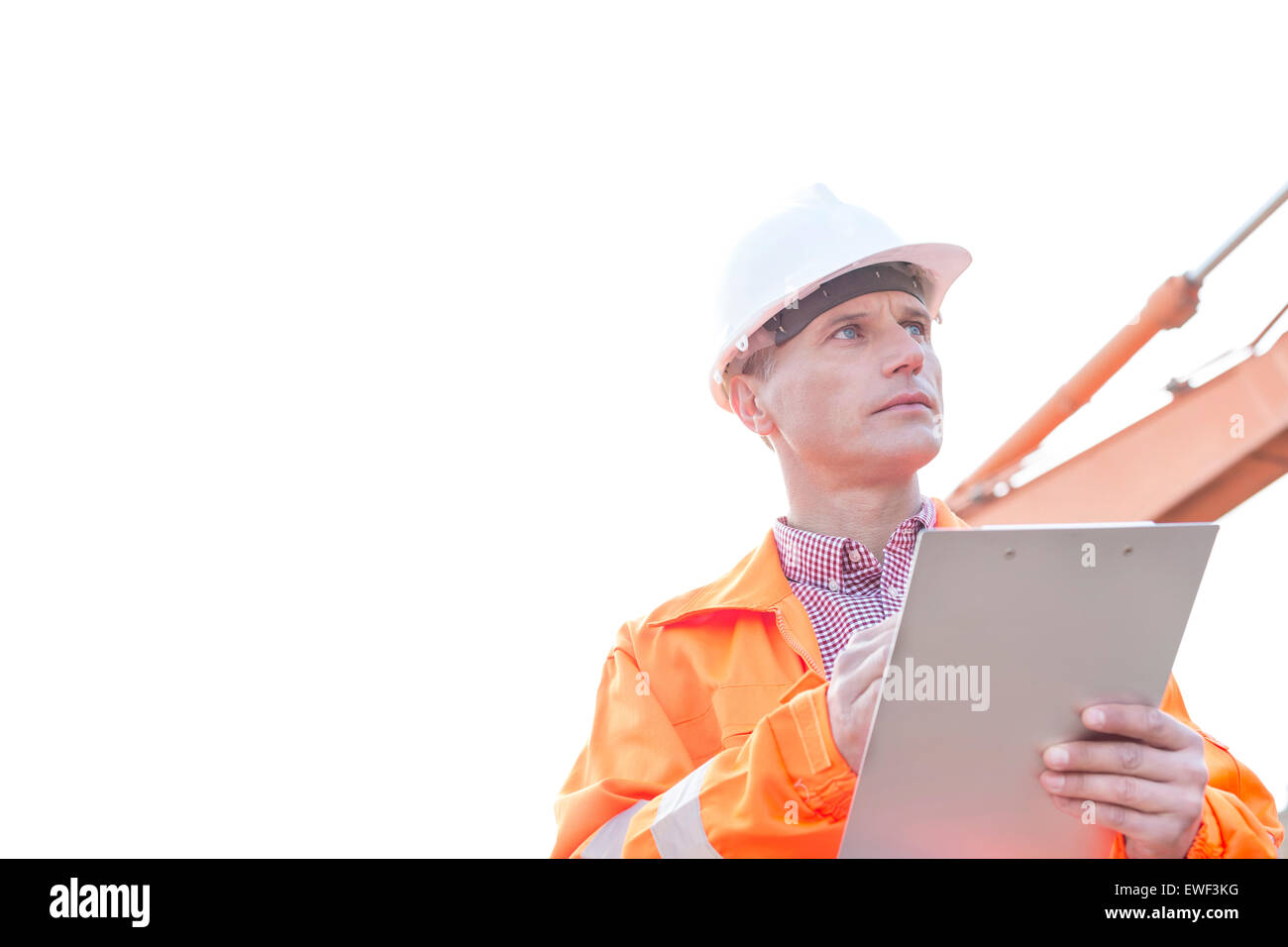 Supervisor looking away while holding clipboard against clear sky Stock Photo