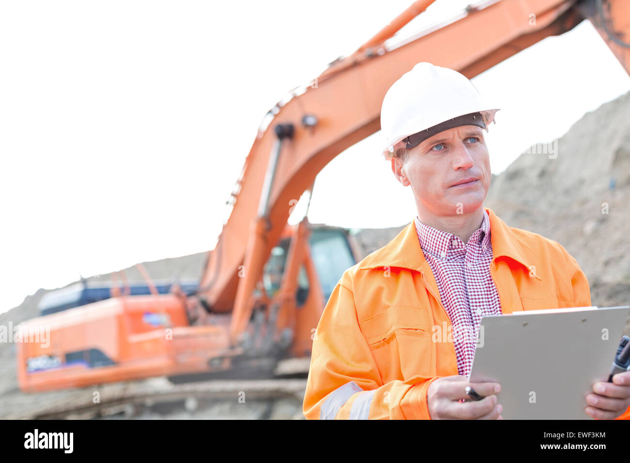 Supervisor looking away while holding clipboard at construction site Stock Photo