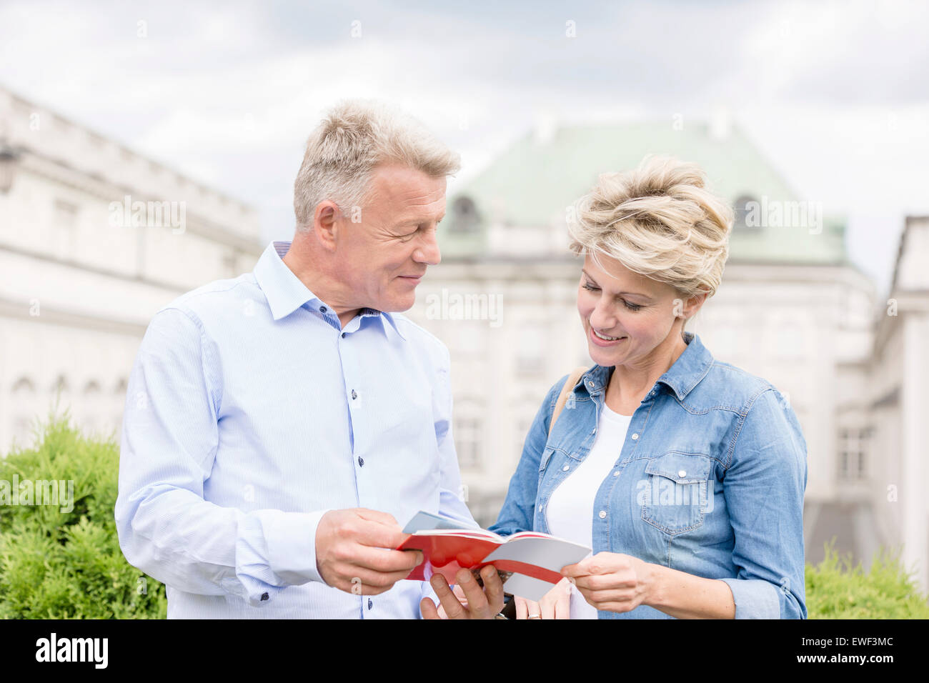 Middle-aged couple reading guidebook outside building Stock Photo