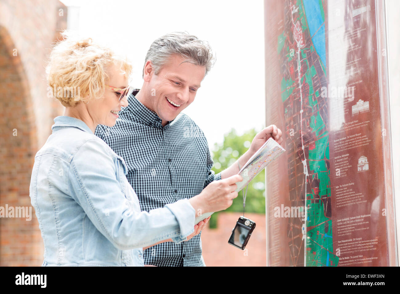 Cheerful middle-aged couple reading map in city Stock Photo