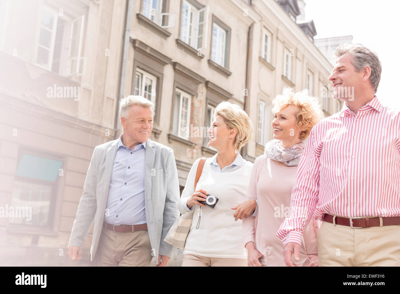 Happy friends talking while walking in city Stock Photo