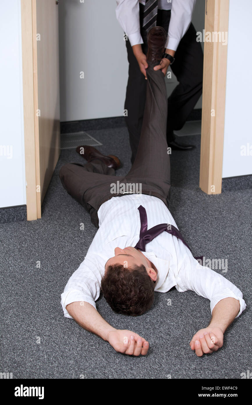 Businessmen pulling colleague's leg at office Stock Photo