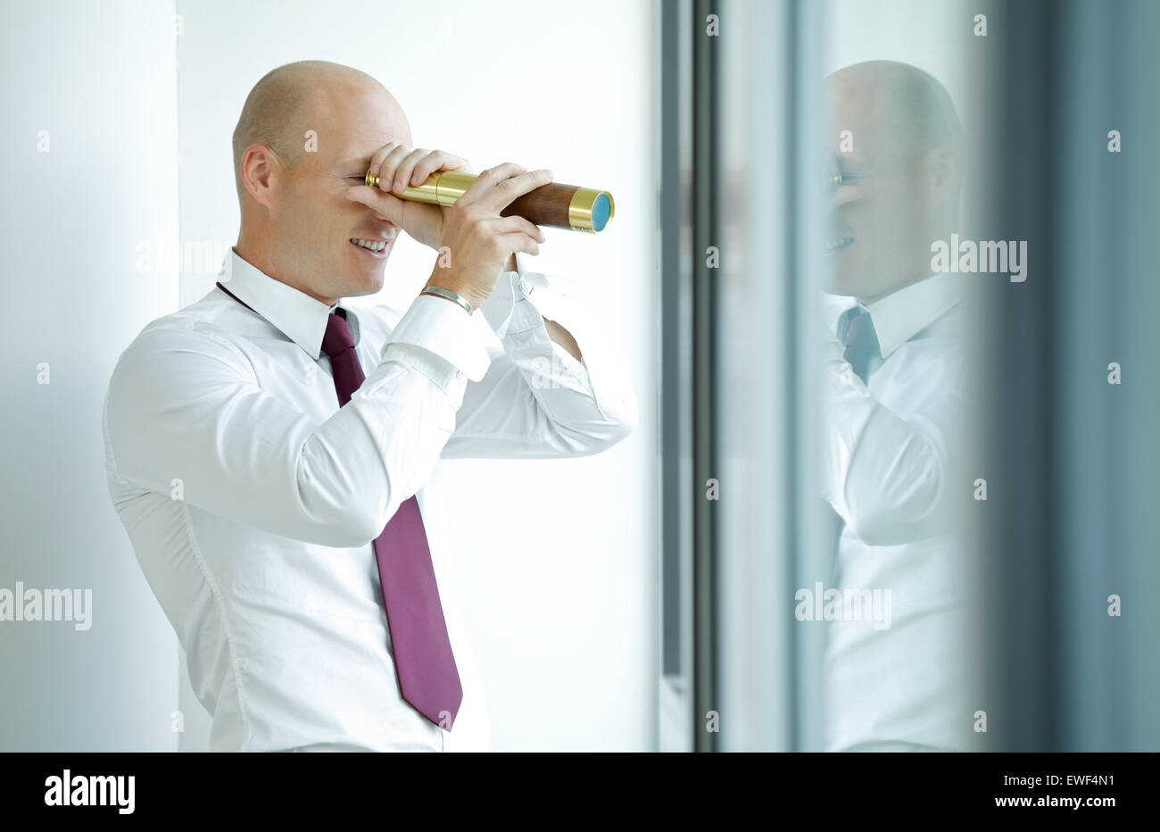 Businessman spying using telescope thru office window Stock Photo