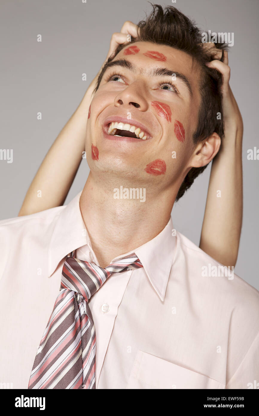 Young caucasian businessman with lipstick kiss mark on his cheek Stock