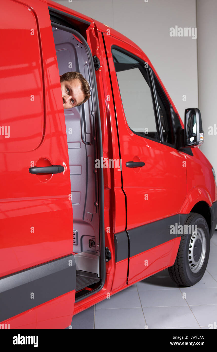Young man peeking through van door Stock Photo