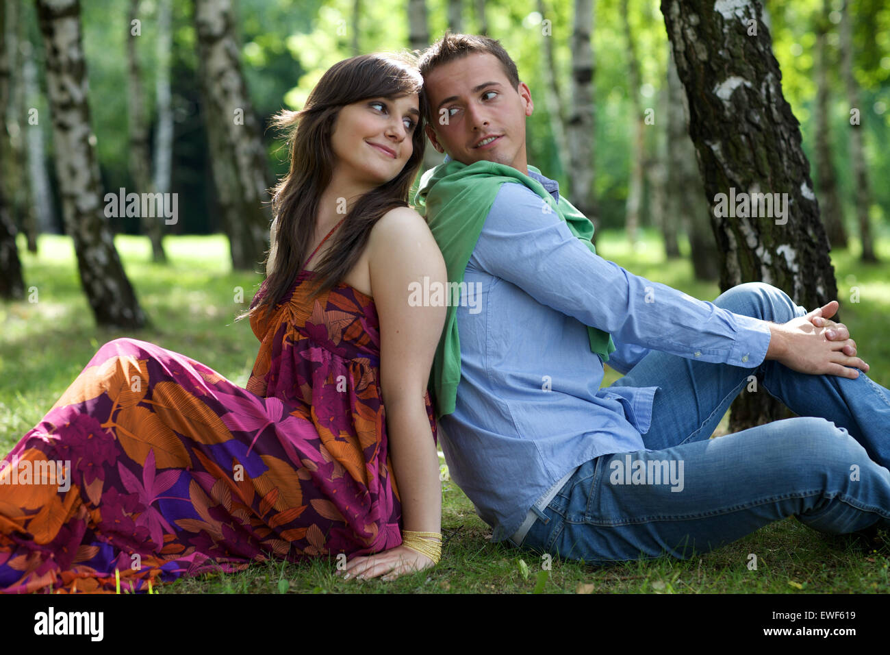 Young couple sitting back to back in park Stock Photo