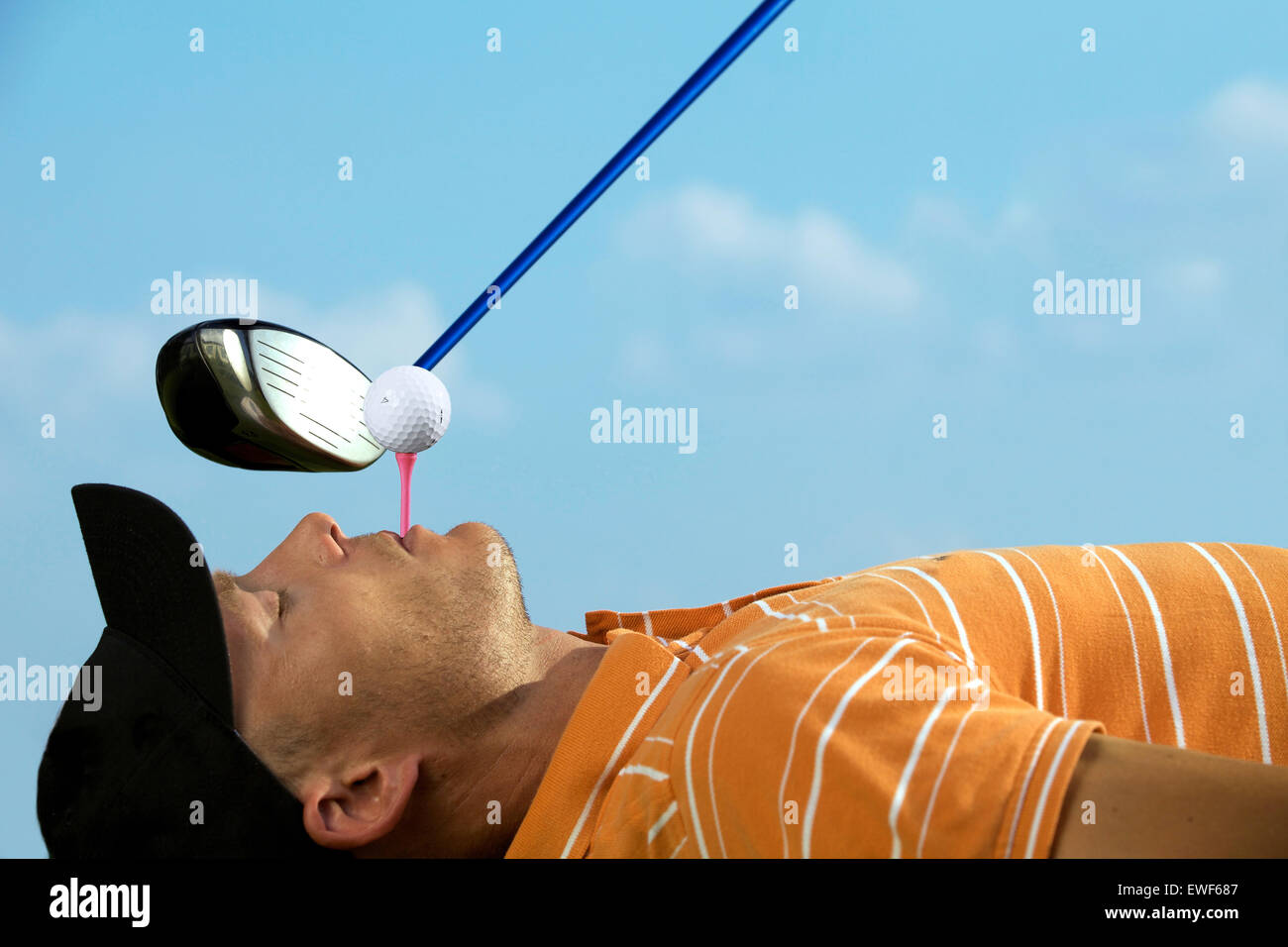 Man balancing golf ball on tee in his mouth Stock Photo