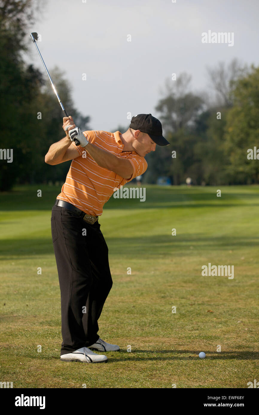 Young man swinging golf club Stock Photo