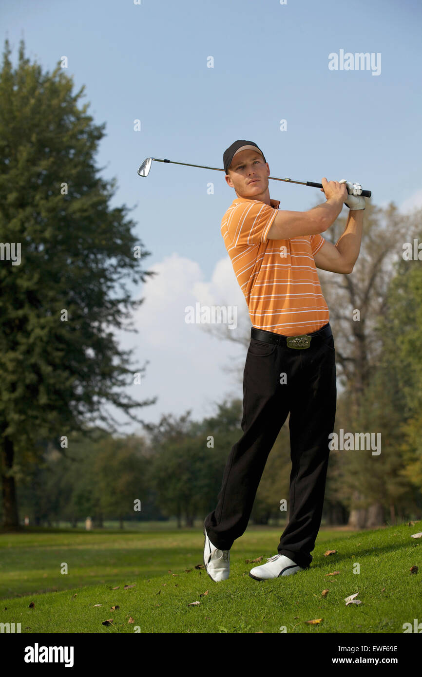 Young man swinging golf club Stock Photo