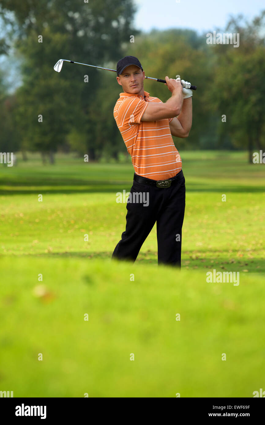 Young man swinging golf club Stock Photo