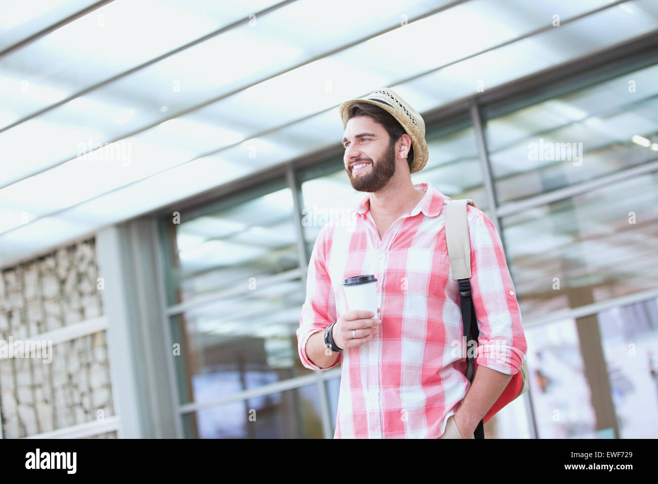 Happy man looking away while holding disposable cup in city Stock Photo