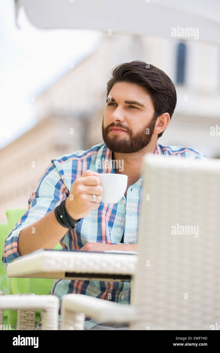 Man looking away while having coffee at sidewalk cafe Stock Photo