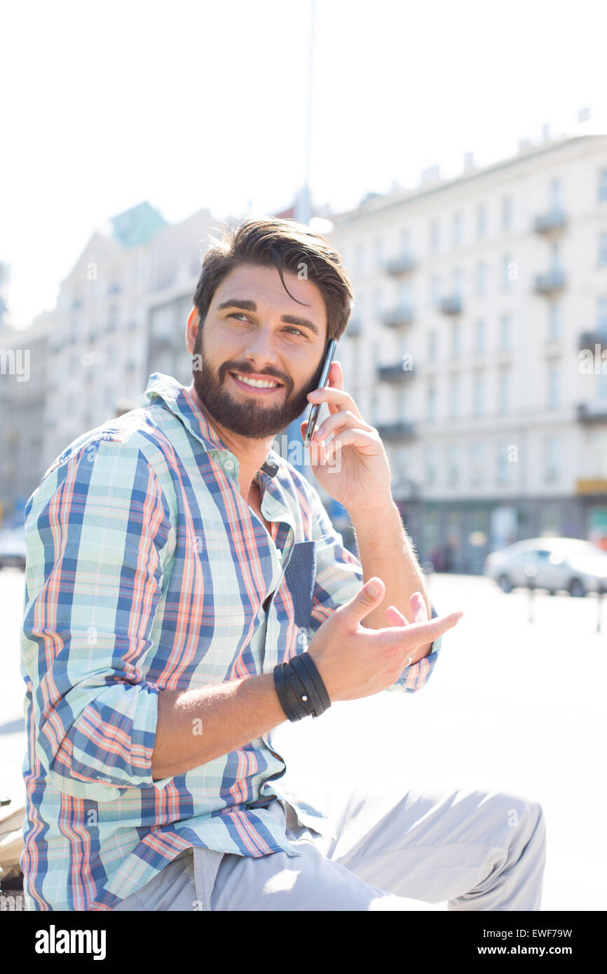 Smiling man looking away while using cell phone in city Stock Photo