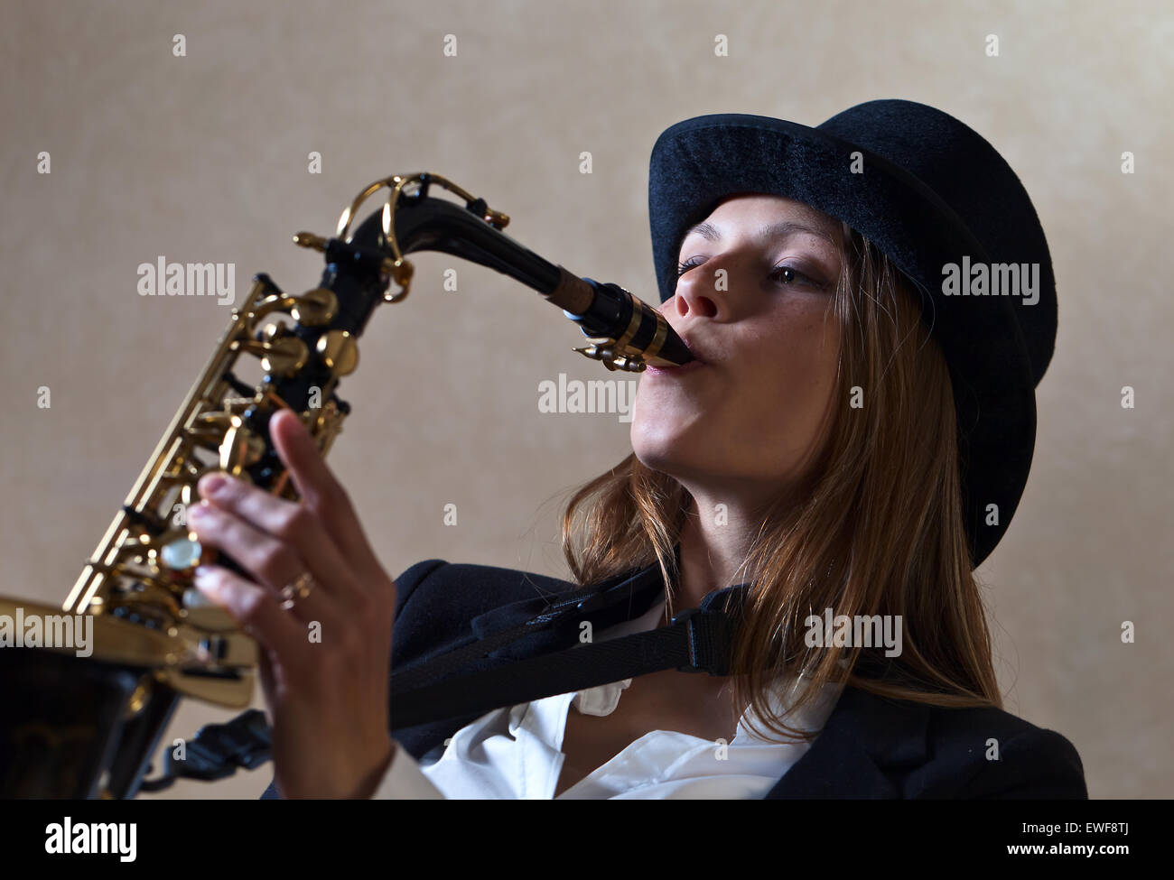 young beautiful woman in black hat with saxophone Stock Photo