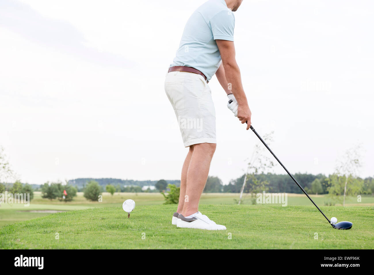 Low section side view of man playing golf against clear sky Stock Photo