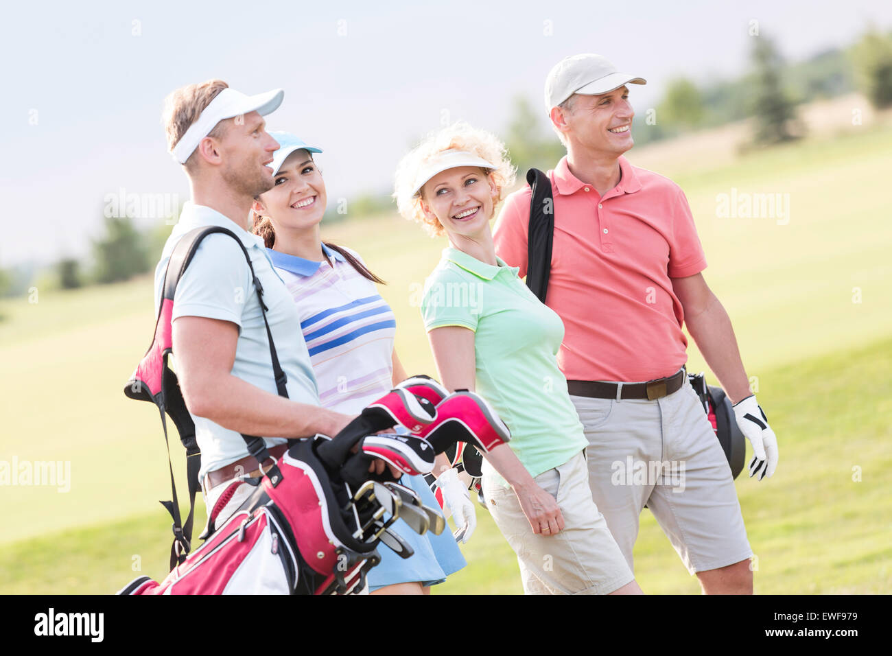 Happy friends walking at golf course Stock Photo