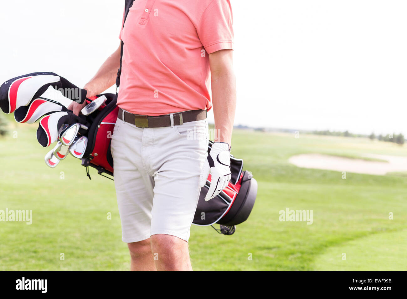 Midsection of man with golf club bag standing at course Stock Photo