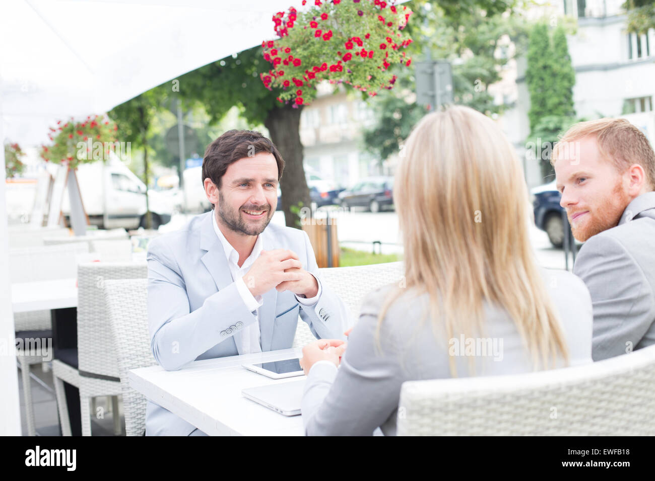 Happy businessman discussing with colleagues at sidewalk cafe Stock Photo