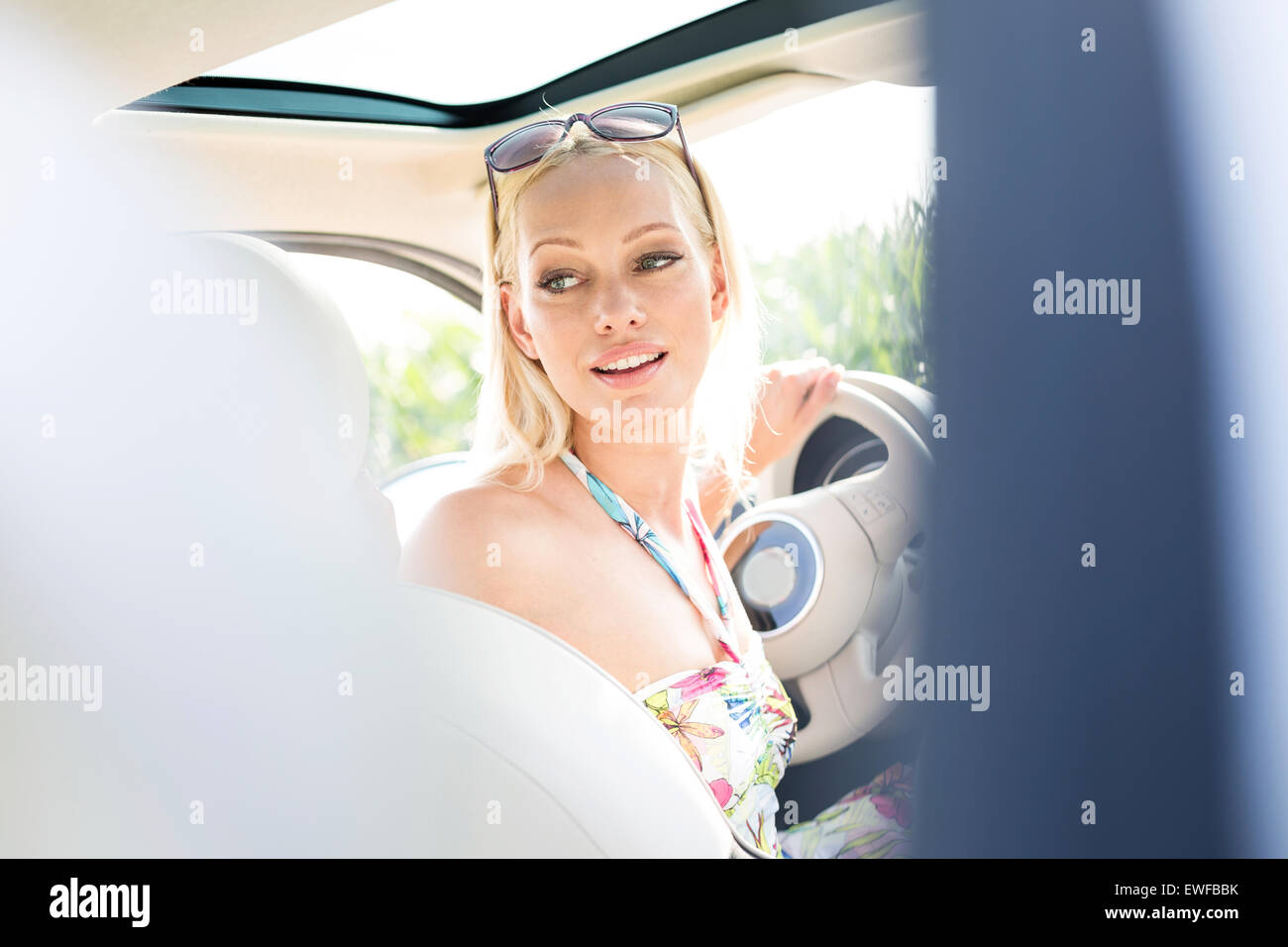 Beautiful woman looking back while driving car Stock Photo