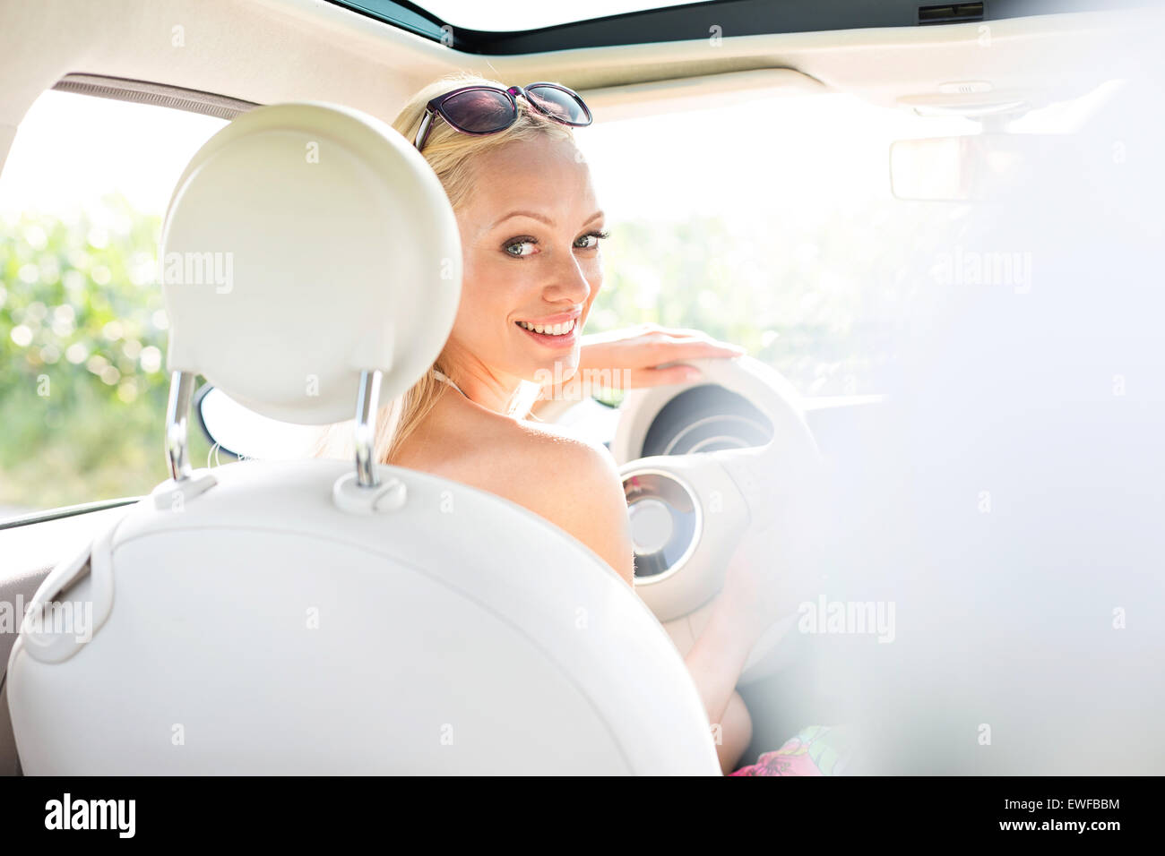 Rear view portrait of happy woman driving car Stock Photo