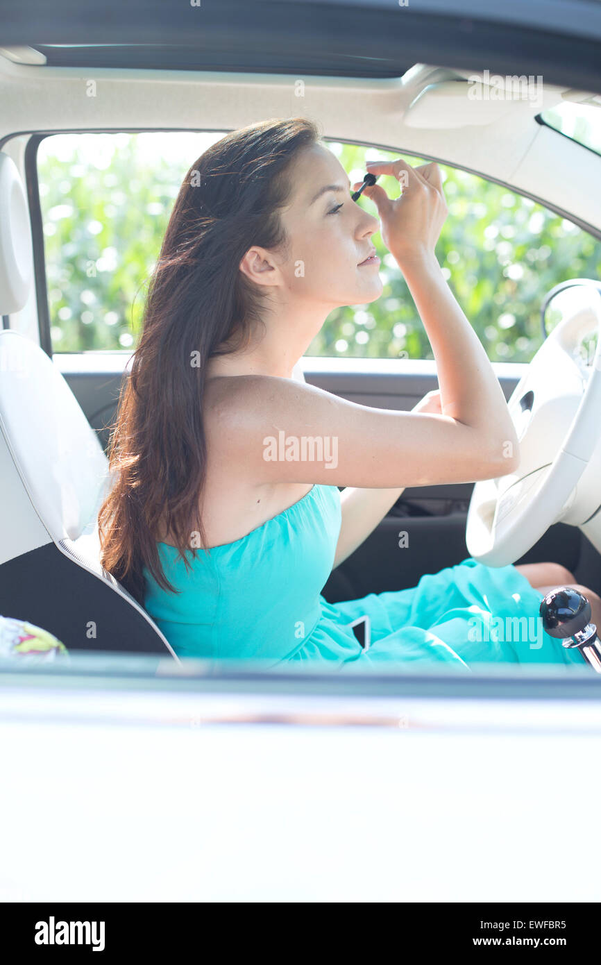 Young woman applying mascara in car Stock Photo