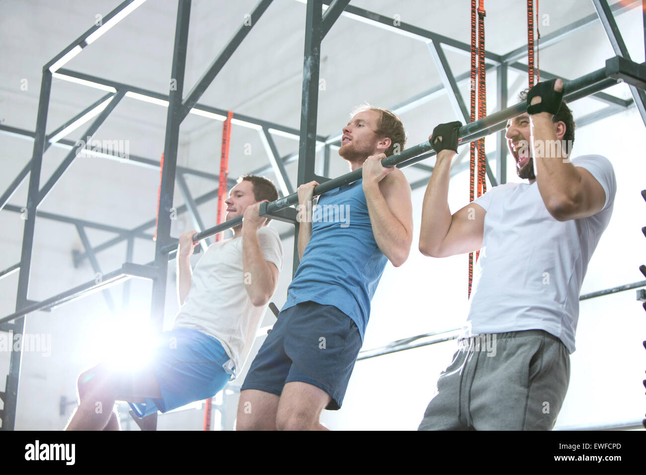 Low angle view of dedicated men doing chin-ups in crossfit gym Stock Photo
