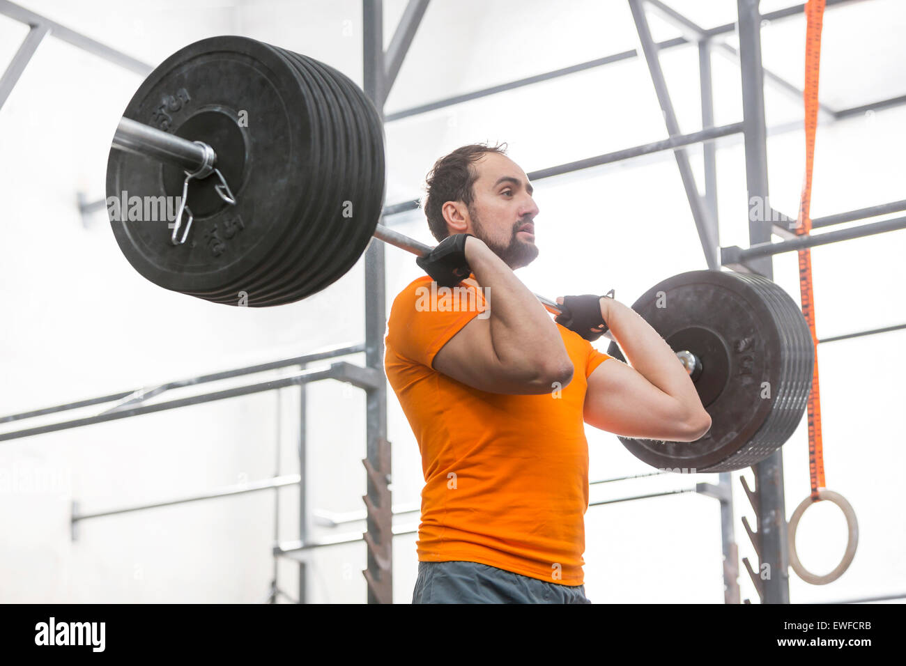 Confident man looking away while lifting barbell in crossfit gym Stock Photo