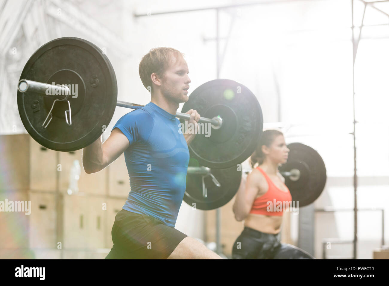 Man and woman lifting barbells in crossfit gym Stock Photo