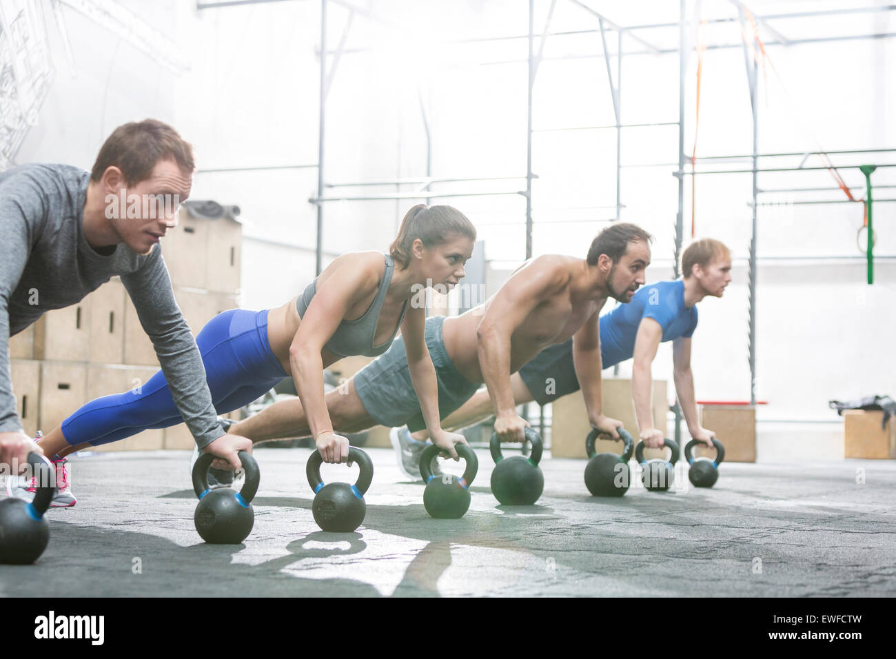Dedicated people doing pushups with kettlebells at crossfit gym Stock Photo