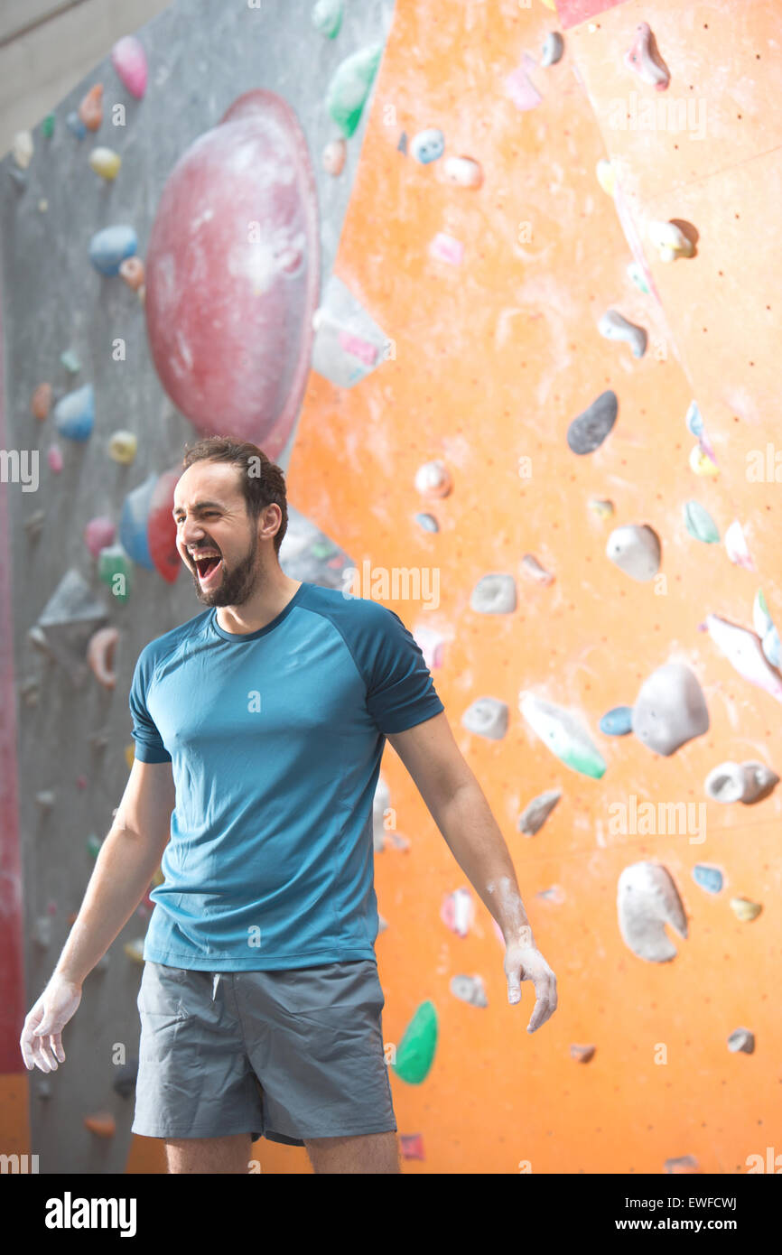 Dedicated man shouting by climbing wall in crossfit gym Stock Photo