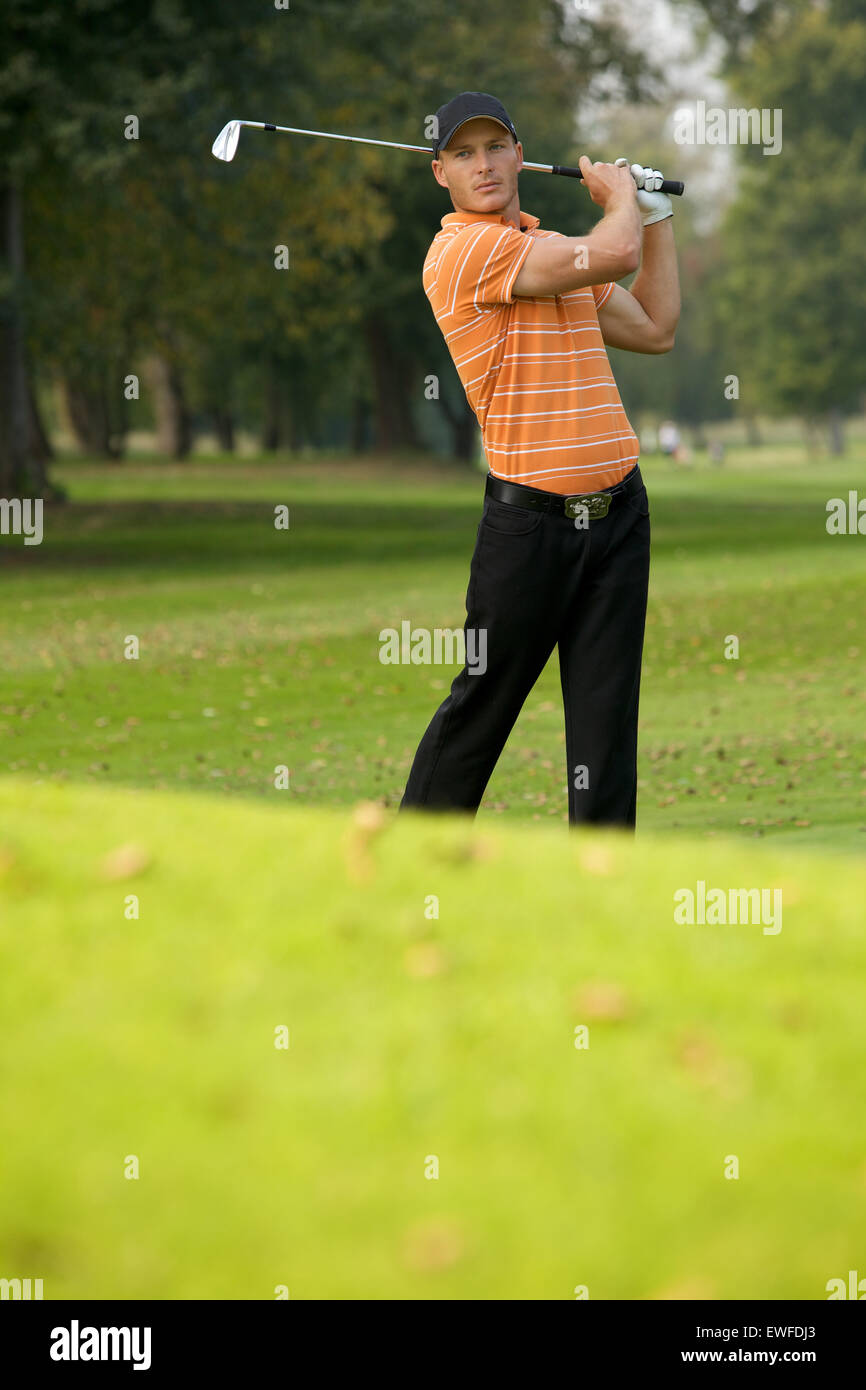 Young man swinging golf club Stock Photo