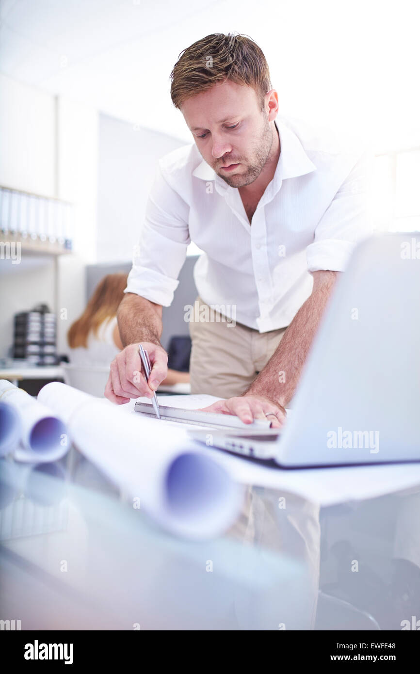 Focused architect drafting blueprint in office Stock Photo
