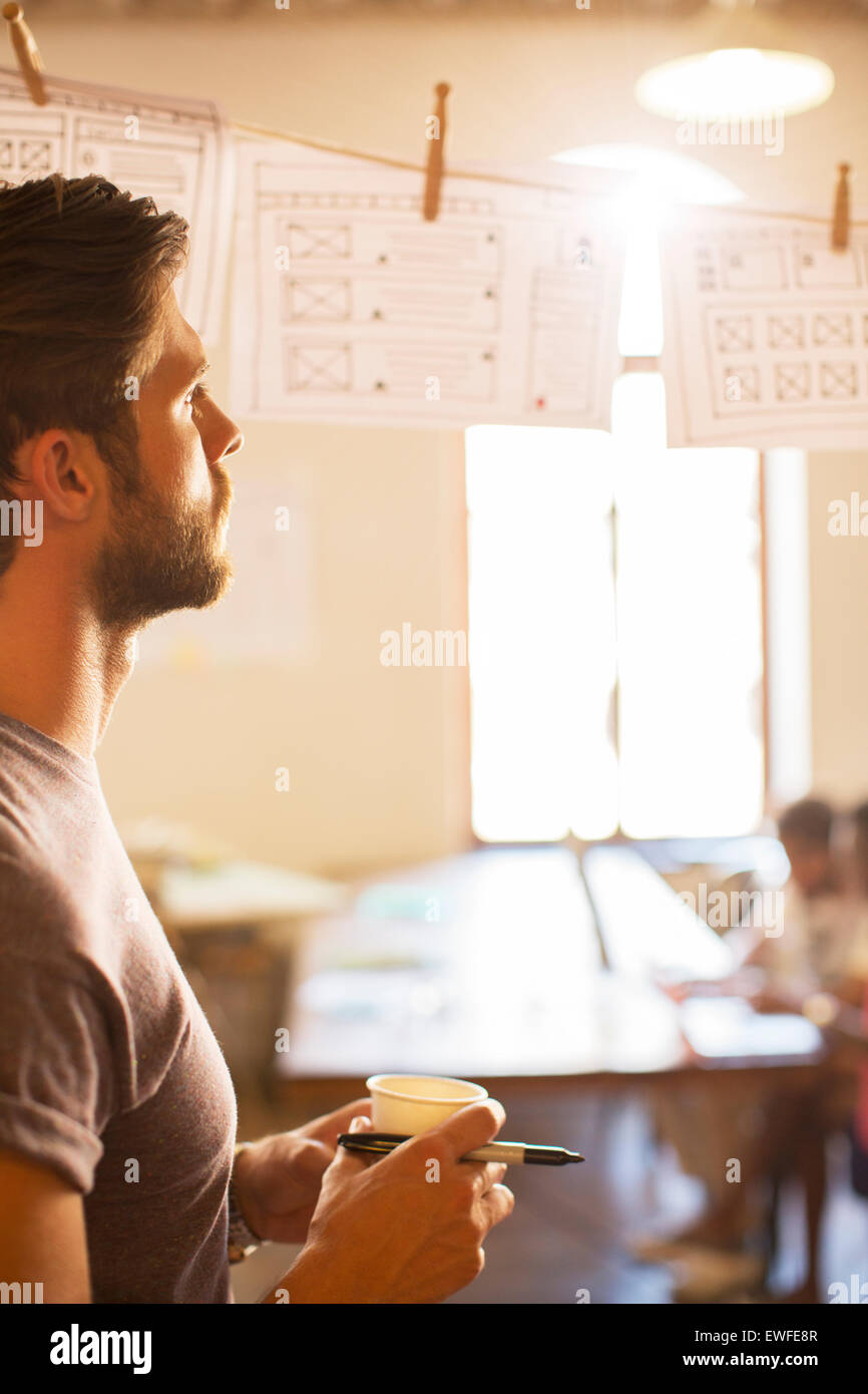 Pensive casual businessman reviewing hanging diagrams in office Stock Photo