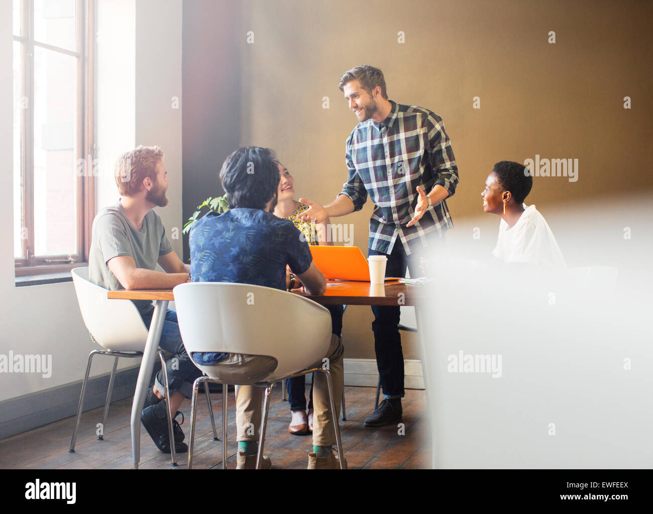 Casual businessman leading meeting at table in office Stock Photo