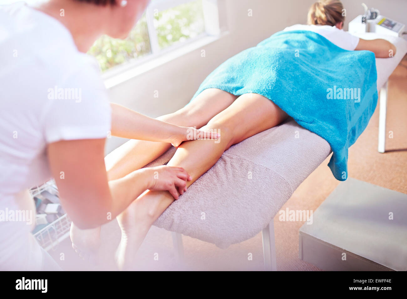 Masseuse massaging woman’s leg Stock Photo