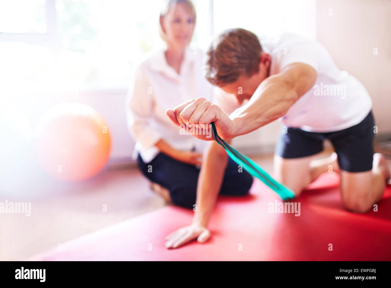 Physical therapist guiding man pulling resistance band Stock Photo