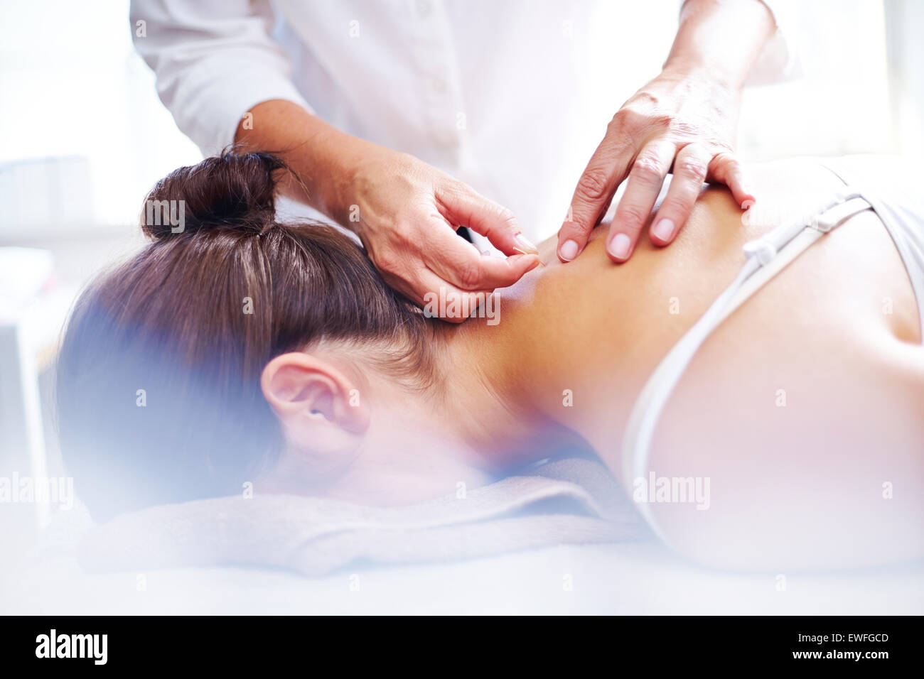 Acupuncturist applying acupuncture needles to woman’s neck Stock Photo