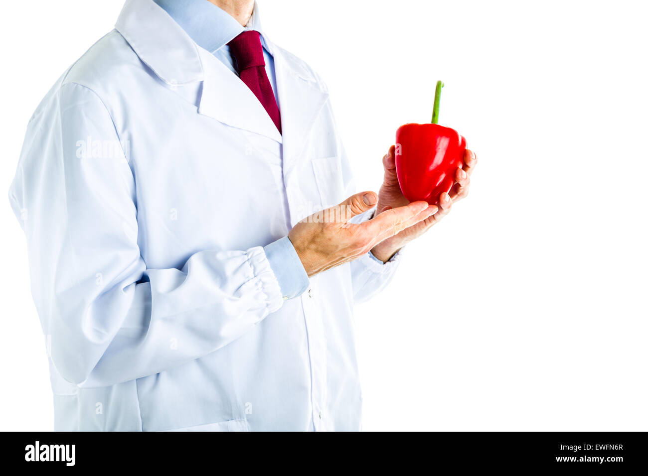 Caucasian male doctor dressed in white coat, blue shirt and red tie is showing a red pepper Stock Photo