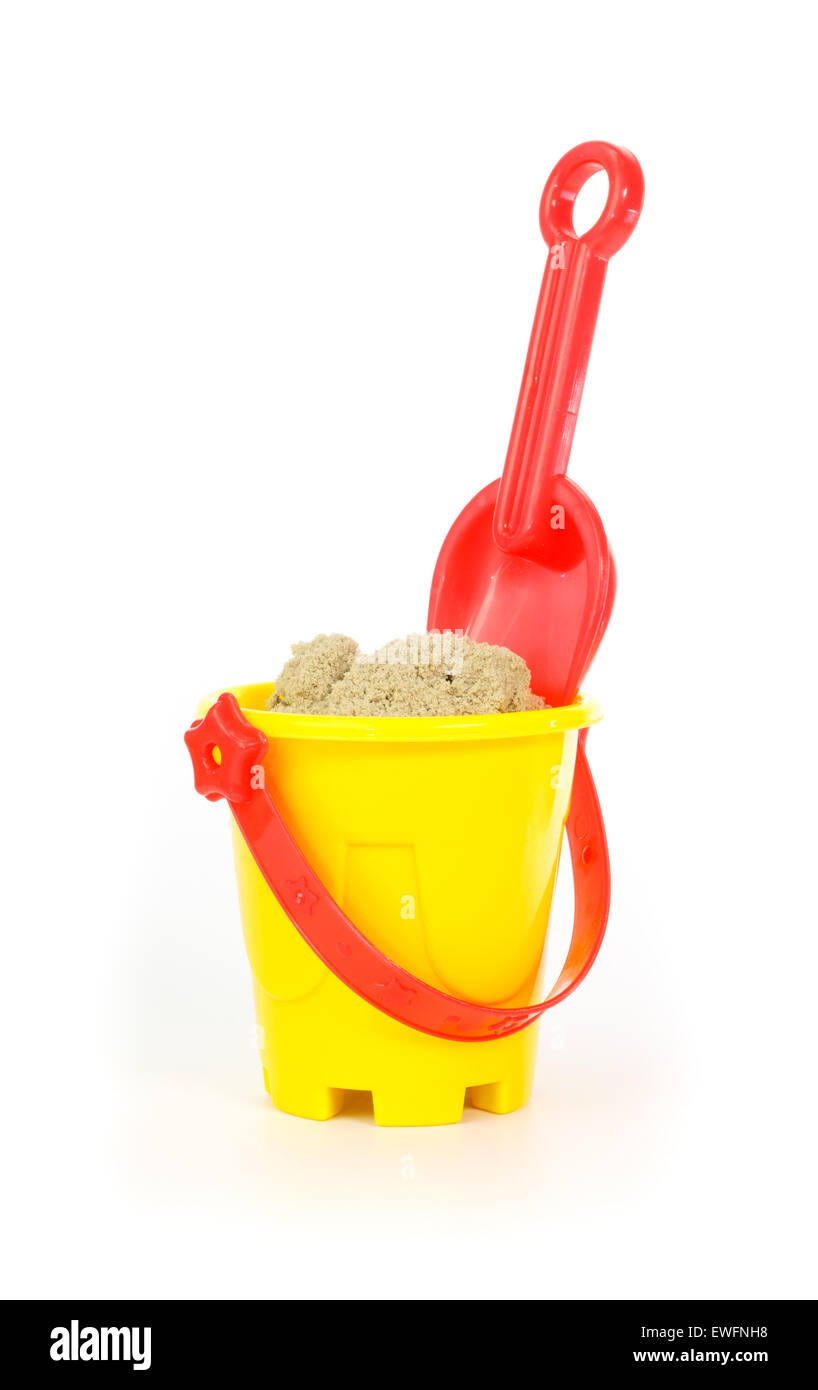 Red toy shovel and a yellow bucket filled with sand against white