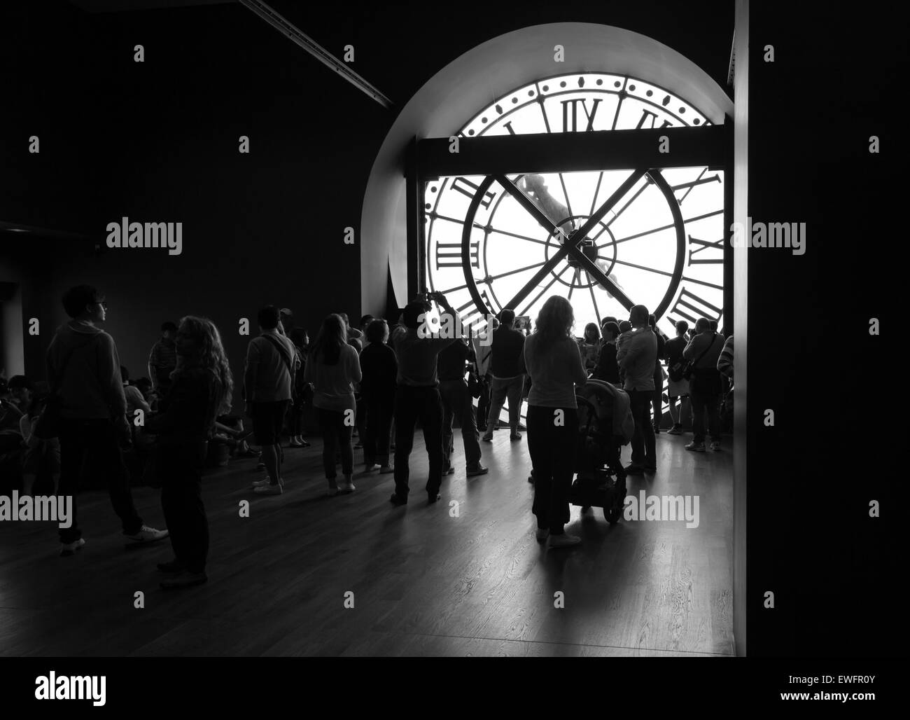 Paris, France - August 10, 2014: Tourists and visitors near the famous ancient clock window in Orsay Museum, black and white pho Stock Photo