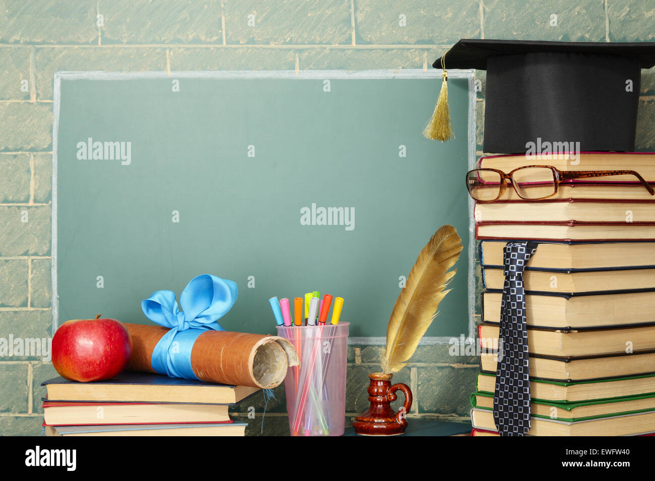 Unusual jesting teacher, books, quill, pen, scroll, apple before blackboard with copy space Stock Photo