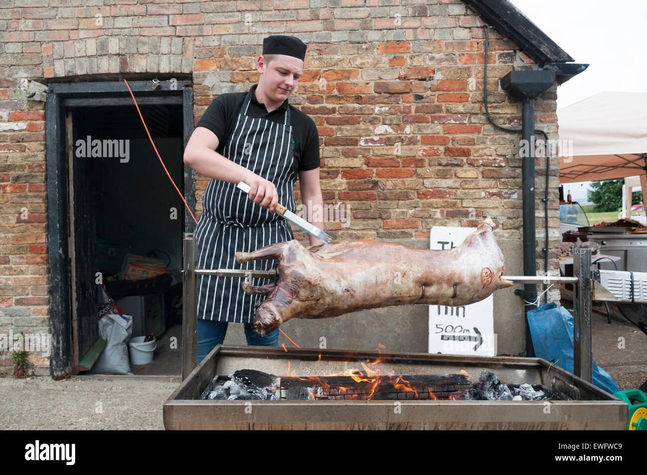 A chef cooking a whole lamb over a charcoal fire on a spit. Stock Photo