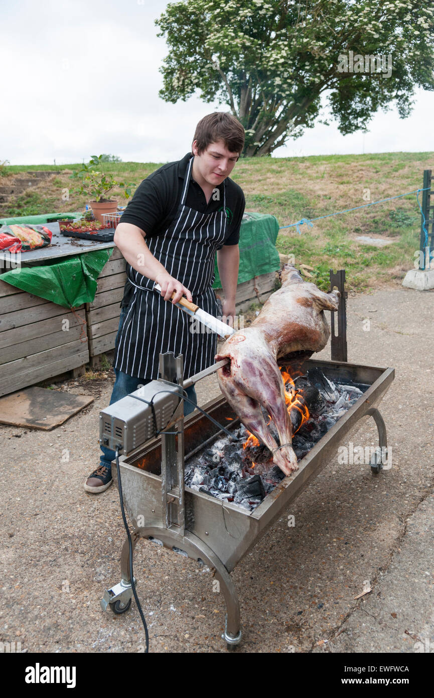A chef cooking a whole lamb over a charcoal fire on a spit. Stock Photo