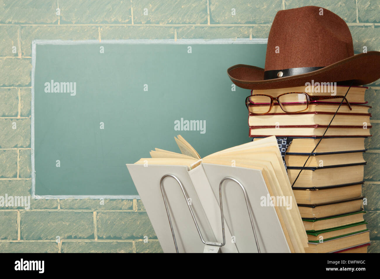 Unusual jesting teacher reading book before blackboard with copy space Stock Photo