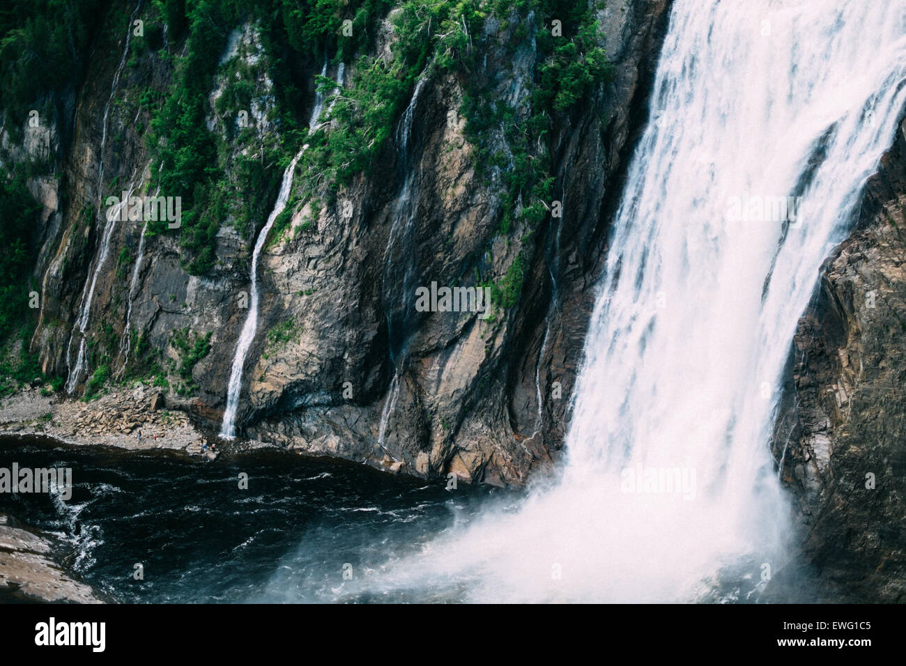A natural waterfall cascades over rocks, creating whitewater rapids and ...