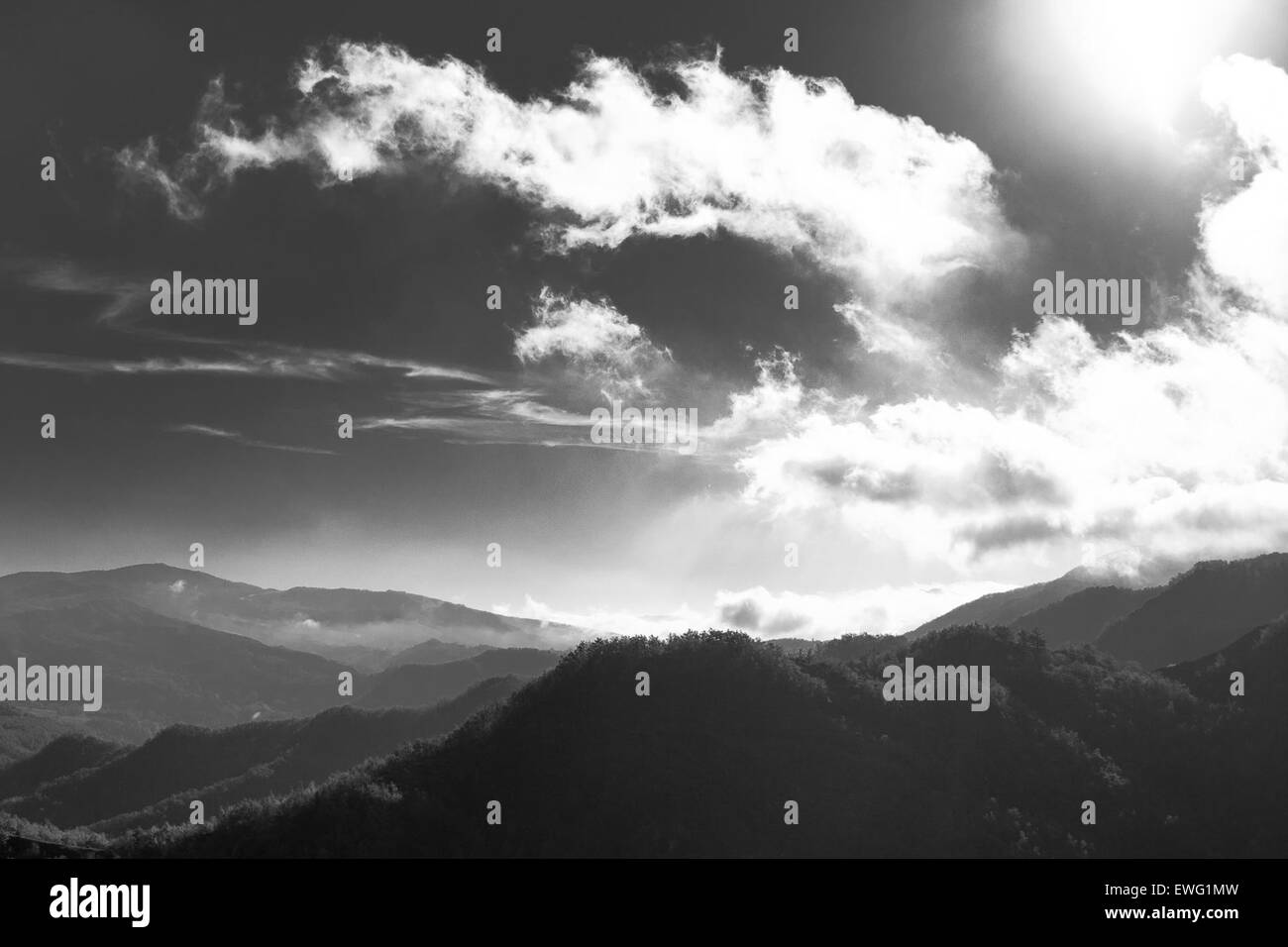 A black and white photograph showing a dramatic landscape of hills and ...