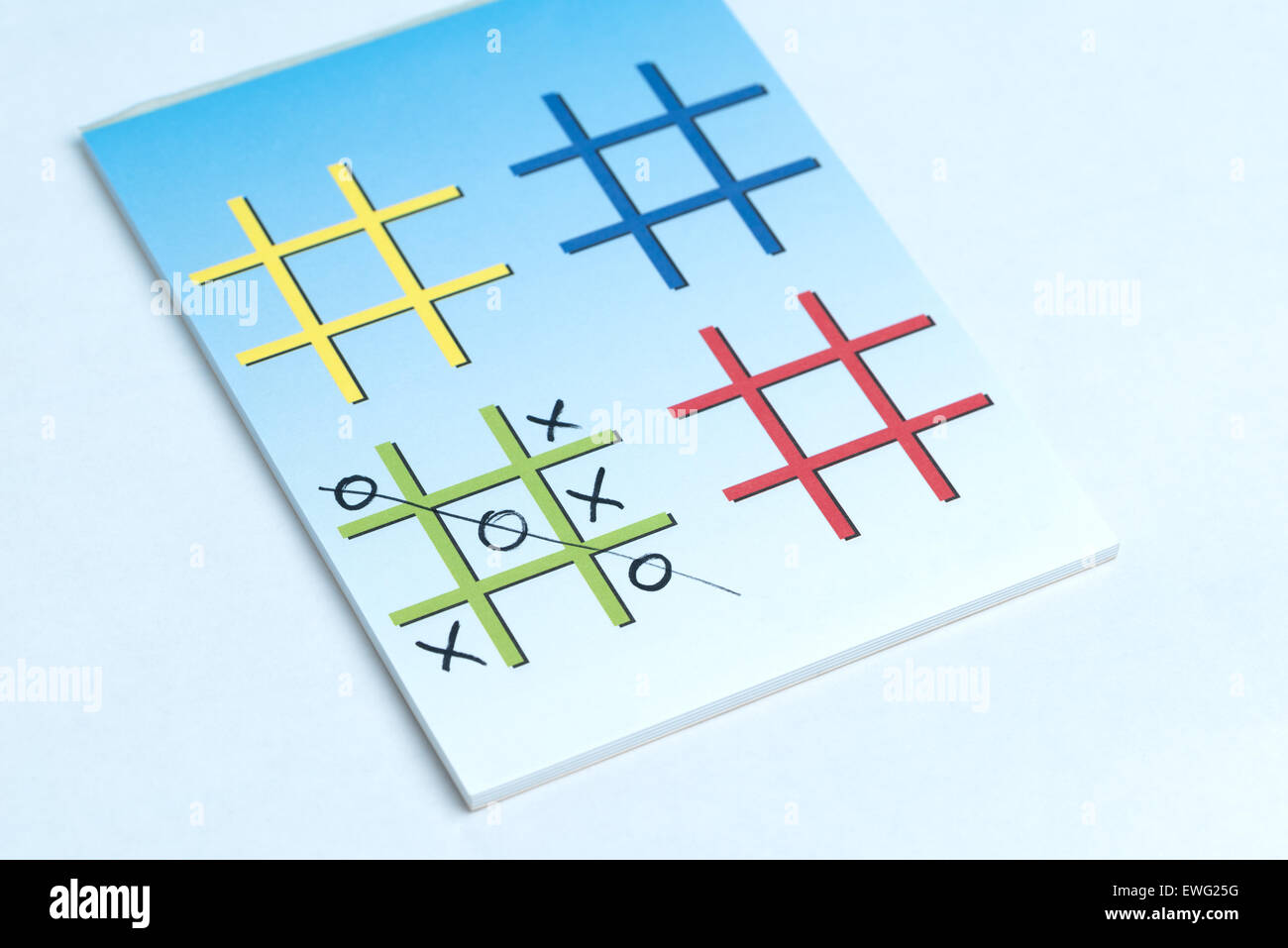 A close up of a game of Xs and Os on a note pad with colorful grids made for playing. Stock Photo